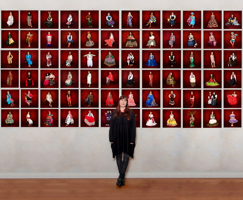 Die Freiburger Fotografin Ellen Schmauss vor einer Wand mit Porträts der Ausstellung. Foto: Schmauss
