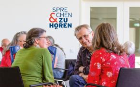Mehrere Menschen sitzen zusammen und sind im Dialog.